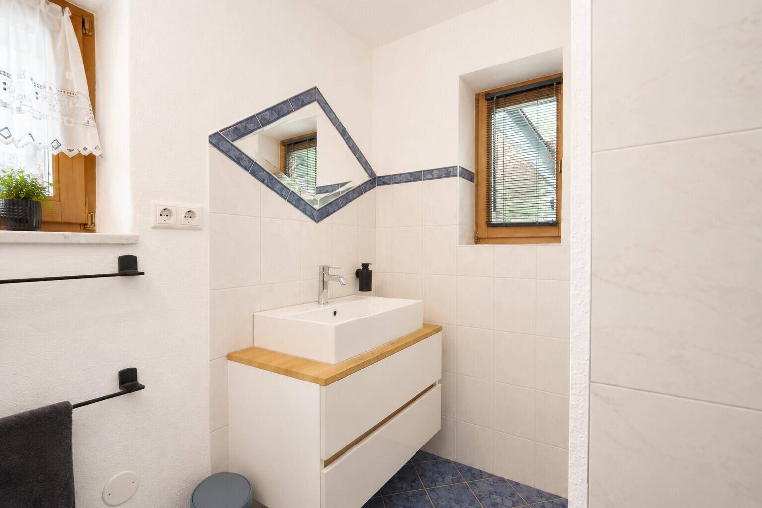 Modernes Gäste-WC mit Waschbecken, Spiegel und blauen Akzentfliesen.
