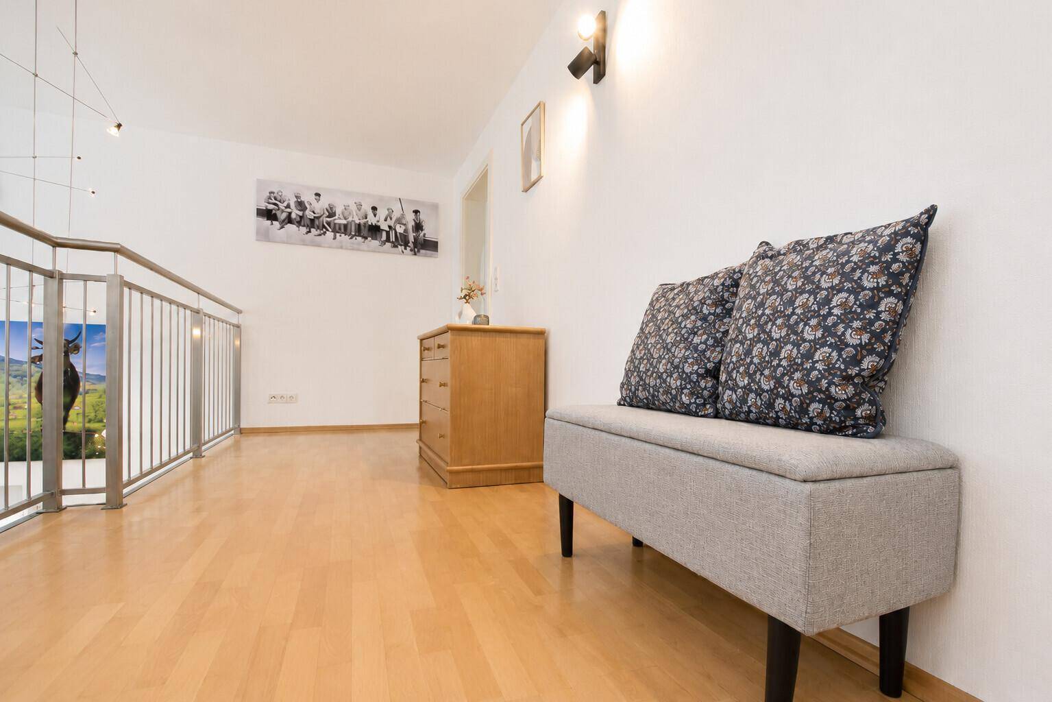 Heller Flur im Obergeschoss mit Holzboden und einer Sitzbank.