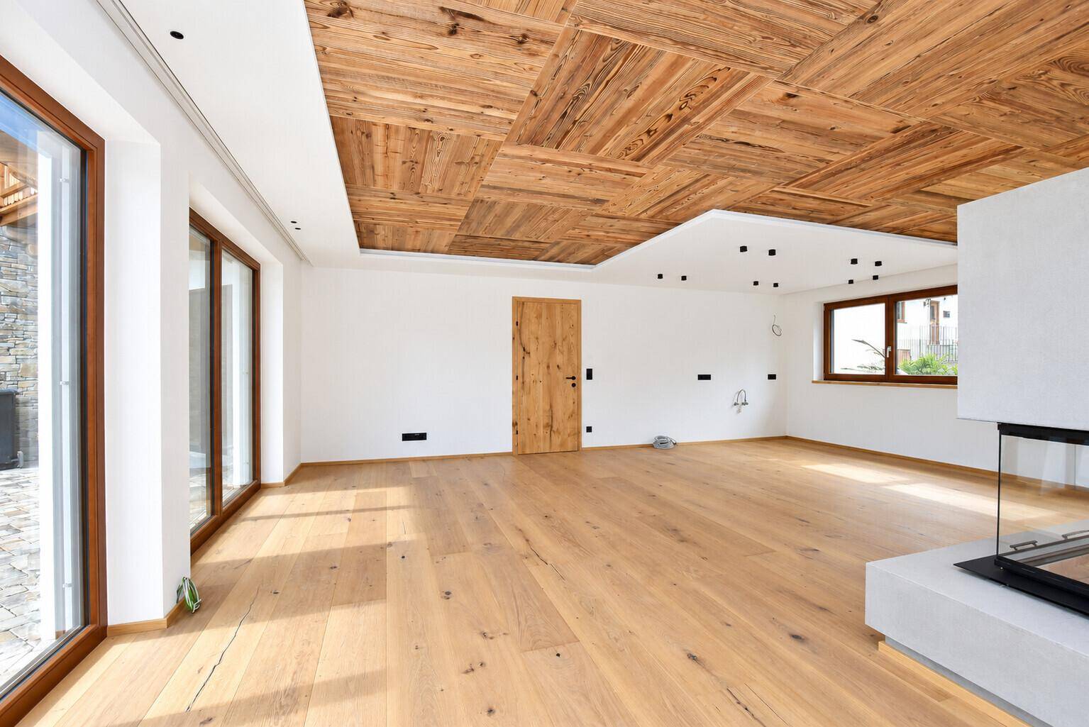 Geräumiger Wohnraum mit Holzboden, moderner Deckenverkleidung und viel Tageslicht.