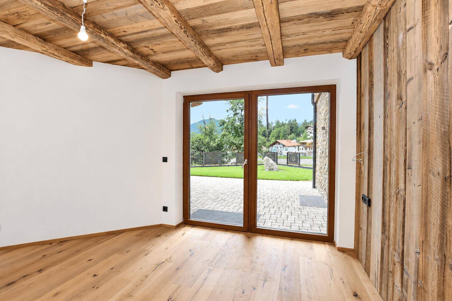 Schlafzimmer mit Holzbalkendecke, Holzboden und direktem Zugang zum Garten.