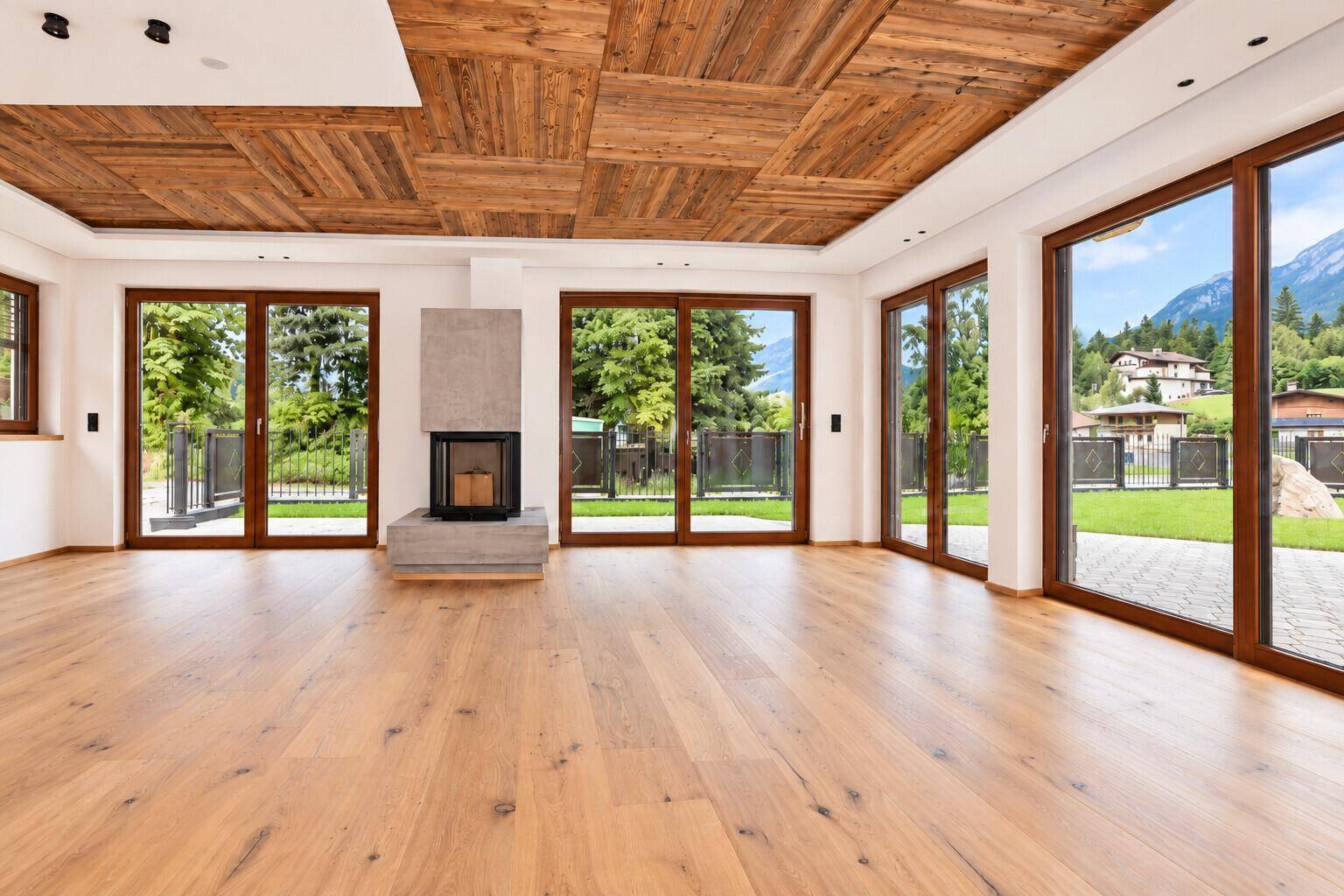 Heller Wohnbereich mit Holzboden, Kamin und großen Fenstern mit Bergblick.