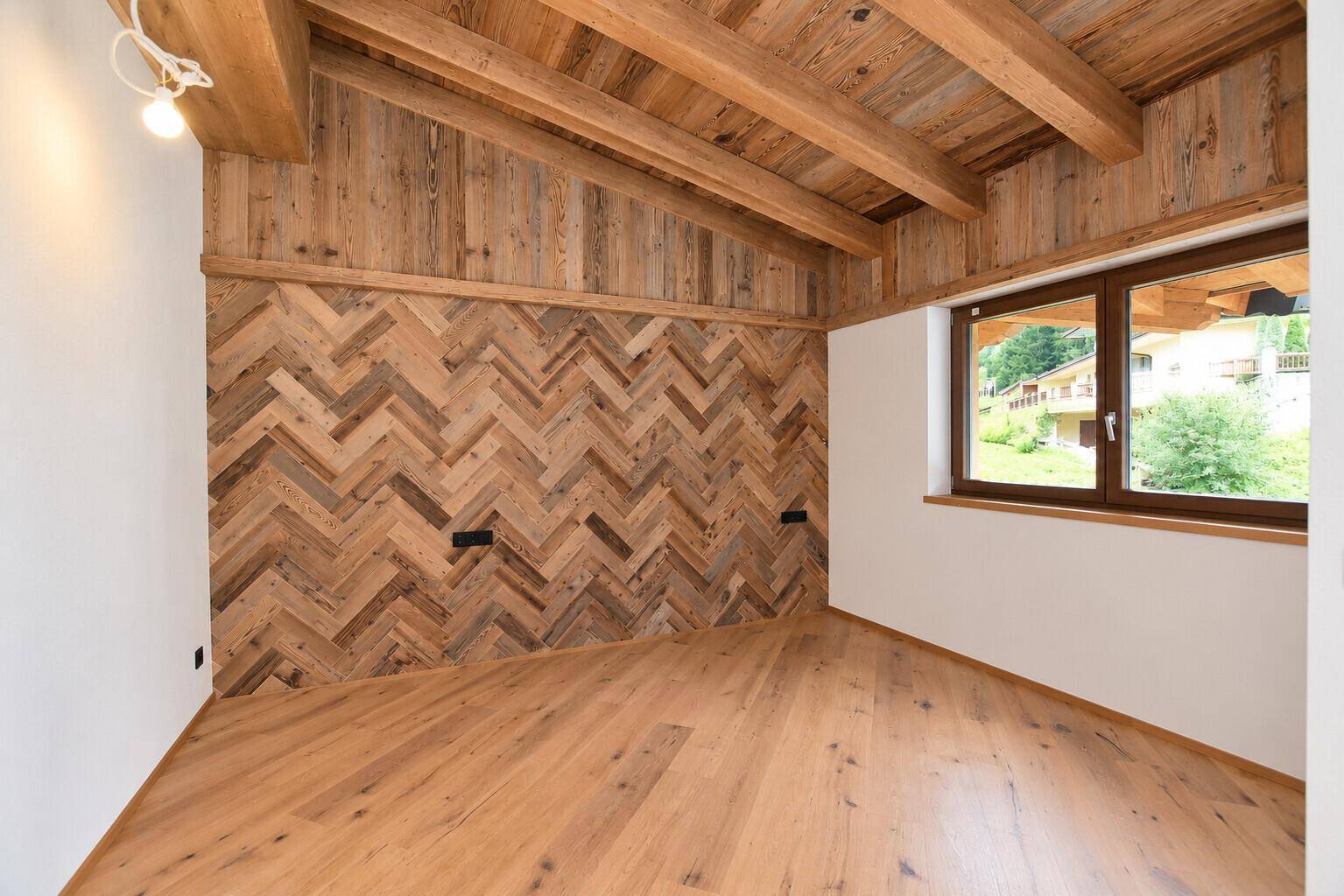 Schlafzimmer mit Holzboden, dekorativer Holzwand im Fischgrätmuster und Holzbalkendecke.