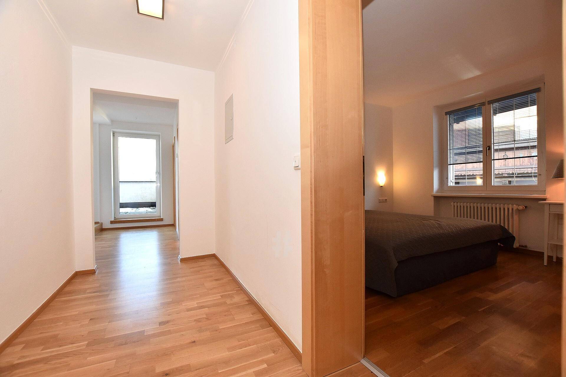 Heller Flur mit Holzboden, der zu einem Schlafzimmer und einem weiteren Raum führt.