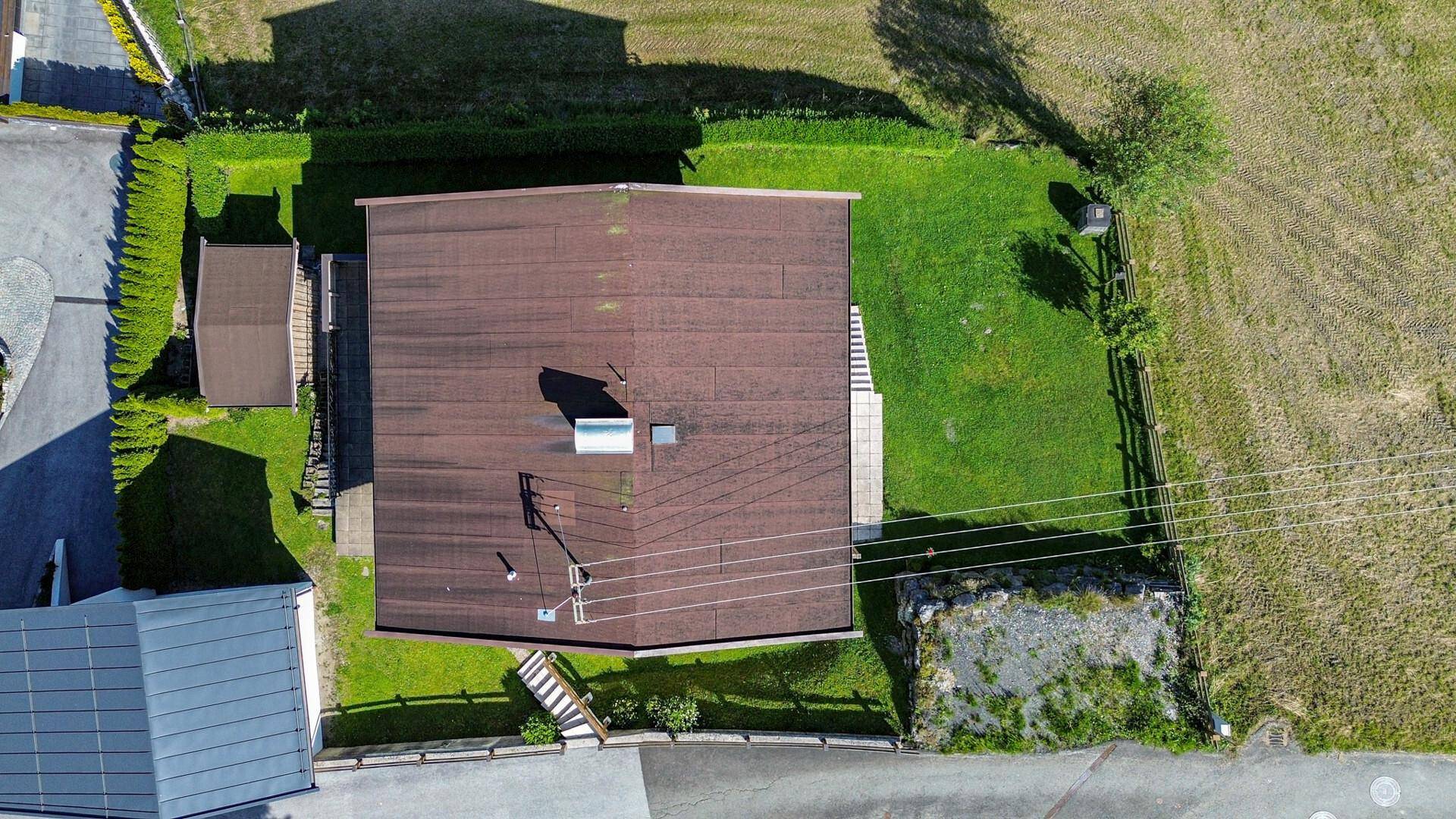 Senkrechte Luftaufnahme des Hauses mit braunem Satteldach und grünem Gartenbereich.