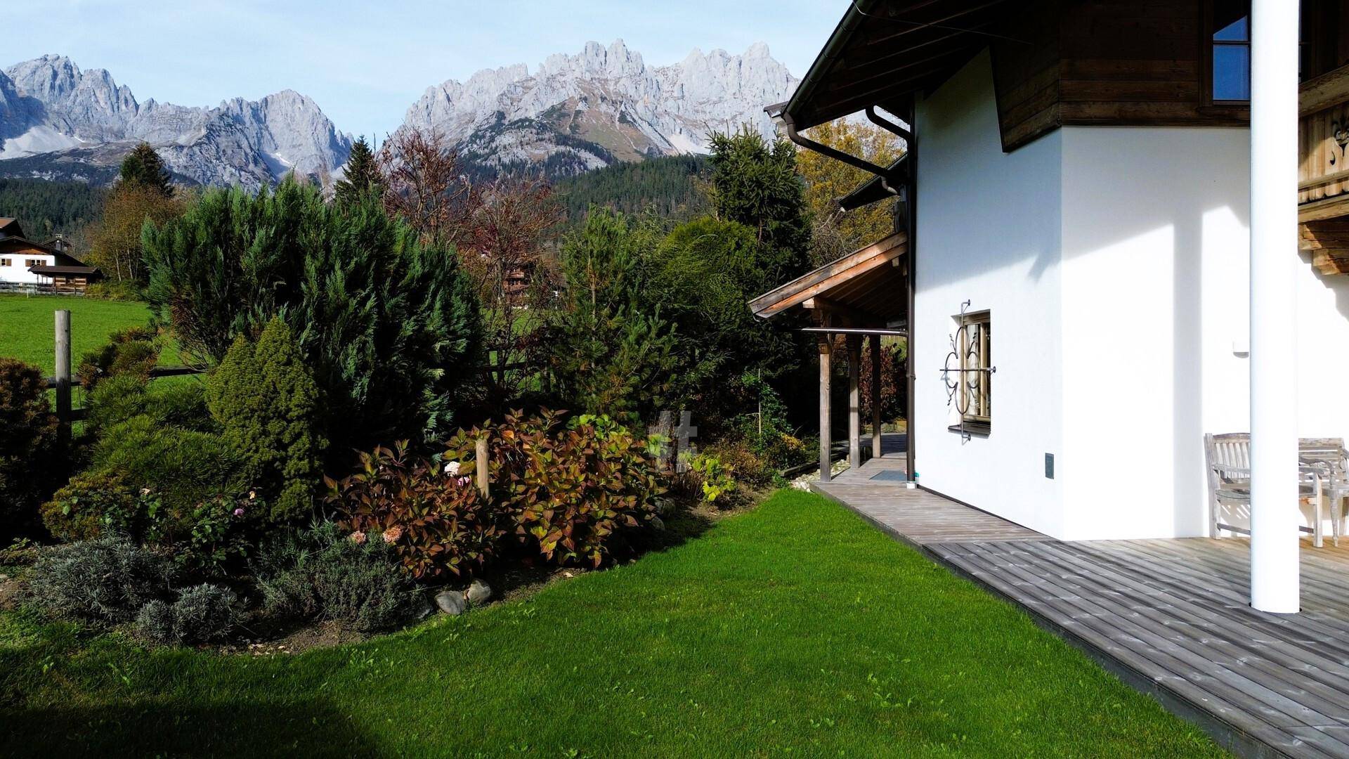Idyllisches Chalet mit gepflegtem Garten und beeindruckendem Alpenpanorama im Hintergrund.