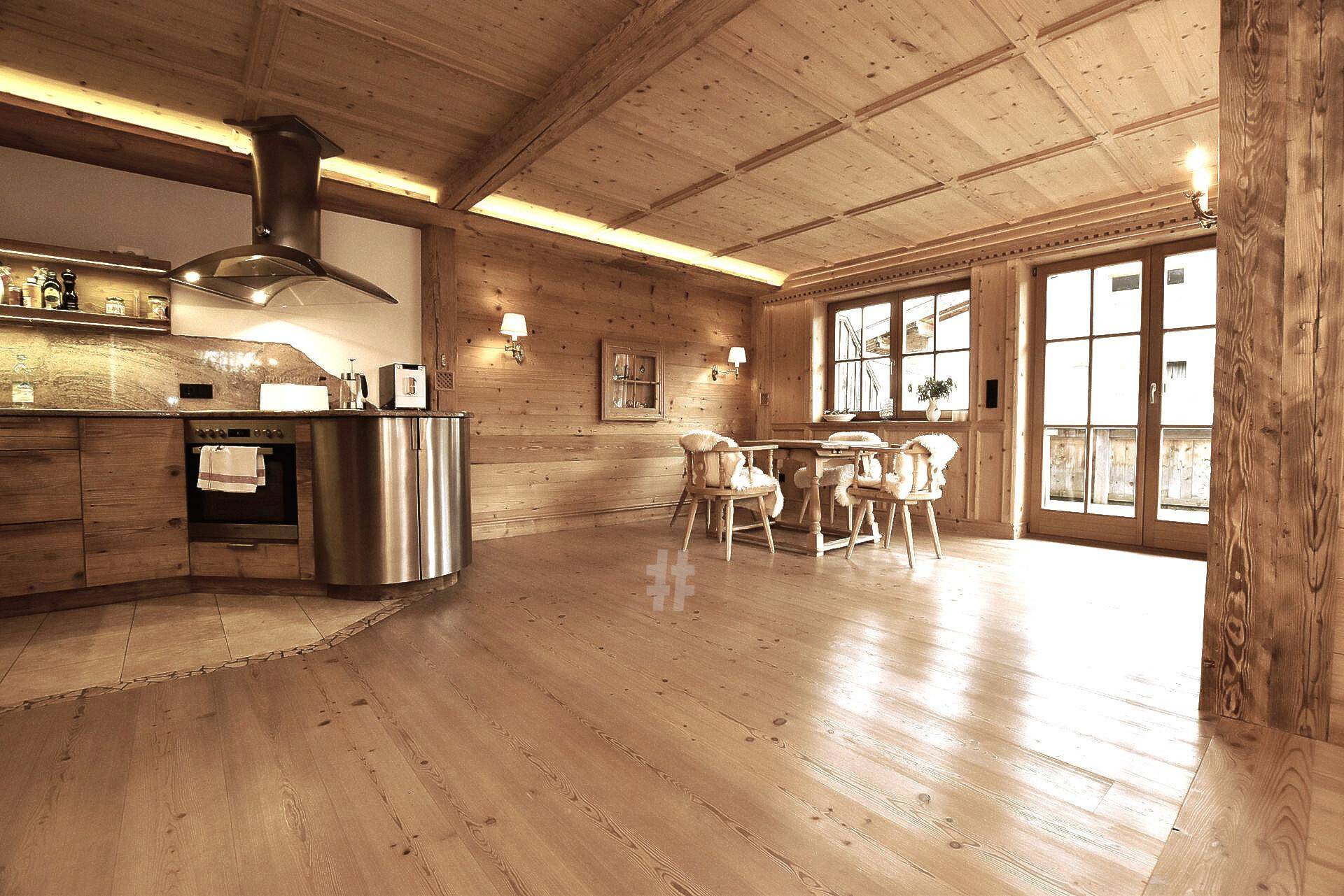 Rustikale Küche mit Holzelementen, modernen Geräten und Essbereich im traditionellen Stil.