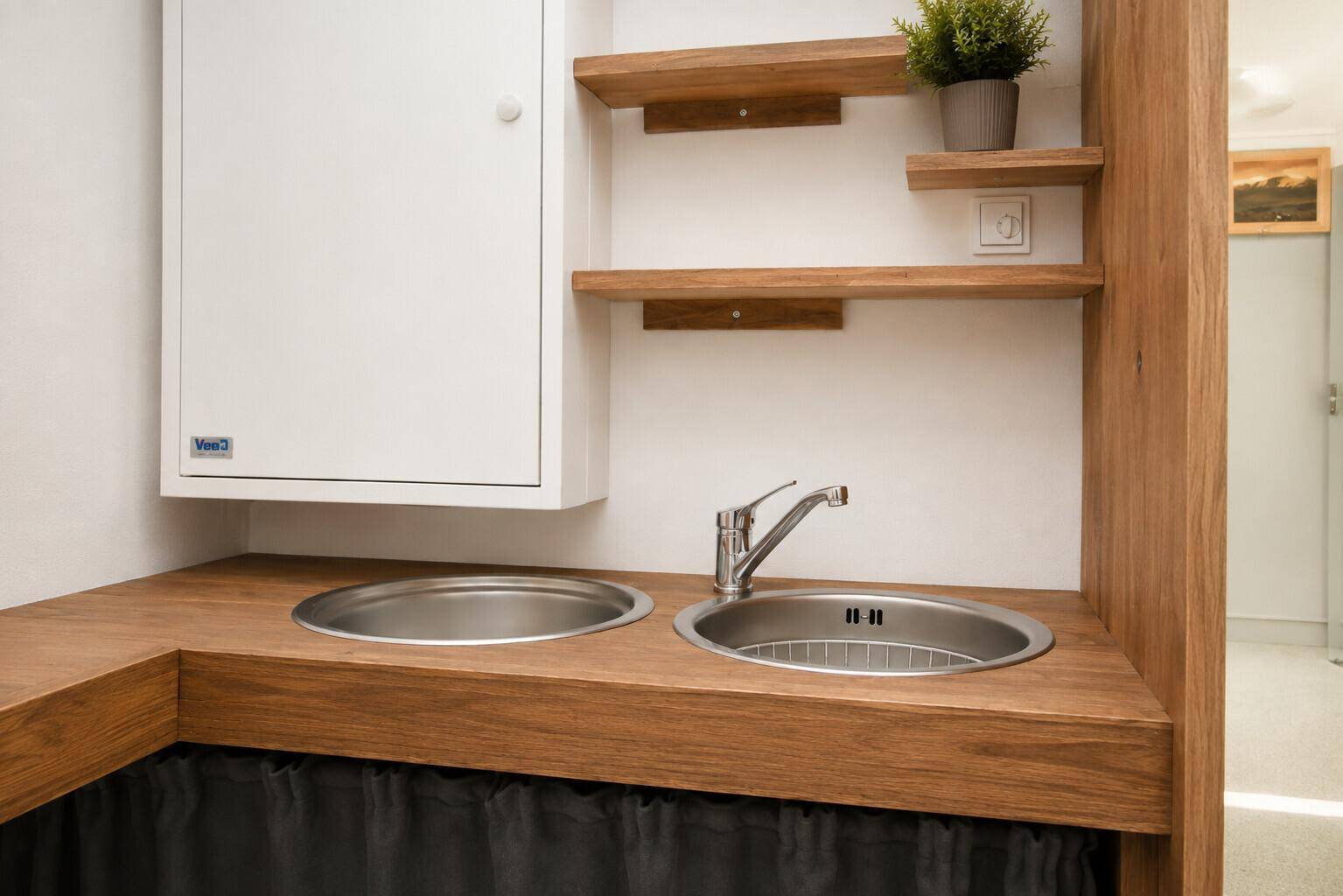 Kleine, funktionale Küchenzeile mit zwei Spülbecken und Holztheke, ideal für eine schnelle Zubereitung.