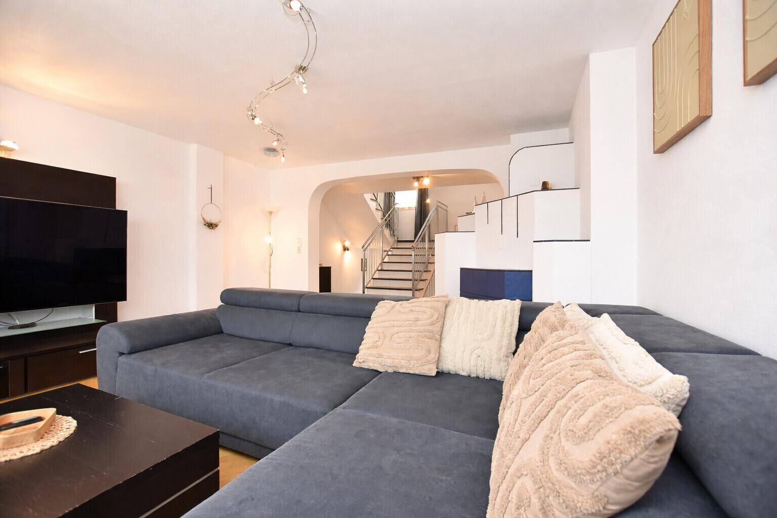 Geräumiges Wohnzimmer mit großem Ecksofa und Blick auf den Treppenaufgang.