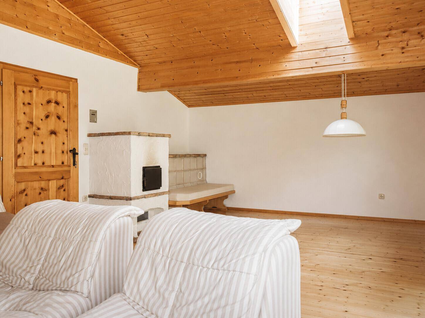 Heller Dachbodenraum mit Holzdachschräge, Dachfenster und einem traditionellen Kaminofen.
