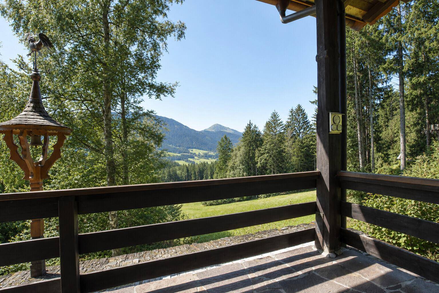 Atemberaubender Bergblick von einem traditionellen Holzbalkon mit weitem Grünblick.