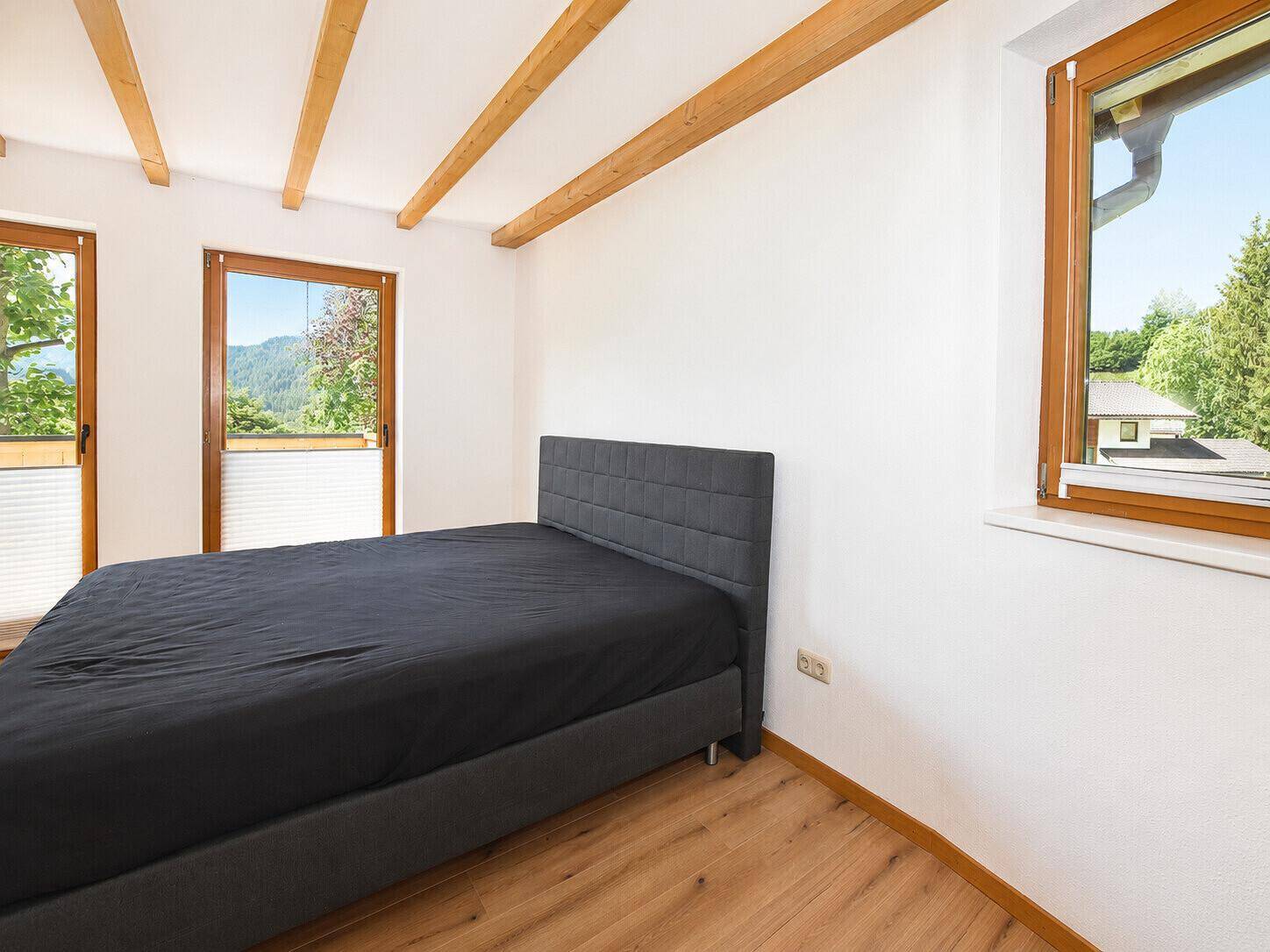 Schlafzimmer mit Holzbalken, Holzboden und großem Bett, hell und freundlich.