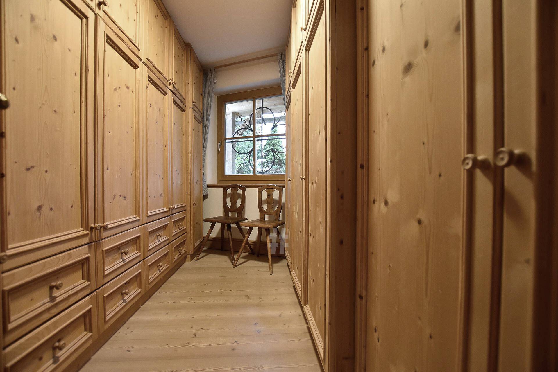 Geräumiger begehbarer Kleiderschrank mit maßgefertigten Holzschränken und Fenster.