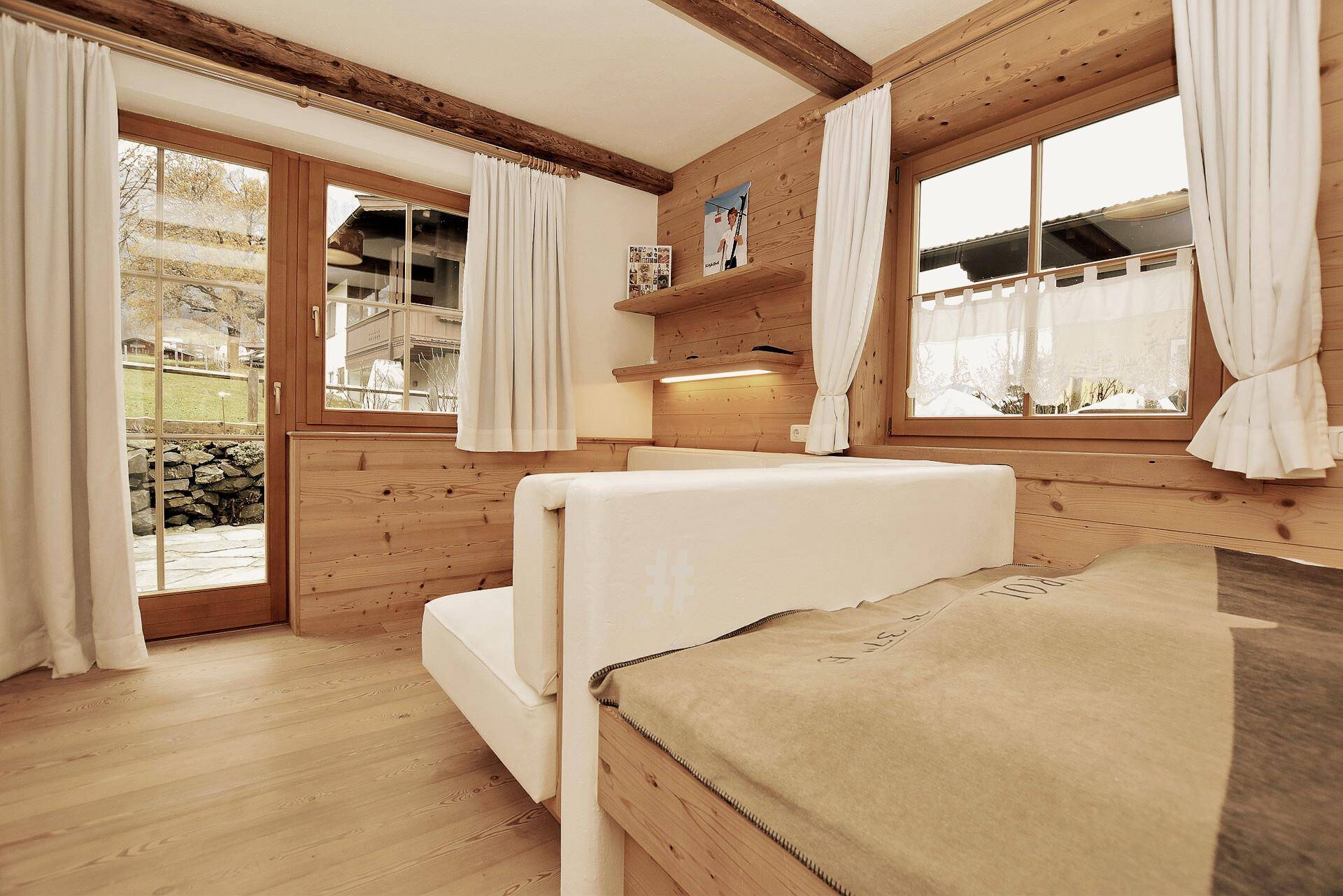 Gemütliches Schlafzimmer mit Holztäfelung, bequemer Liege und Zugang zum Außenbereich.