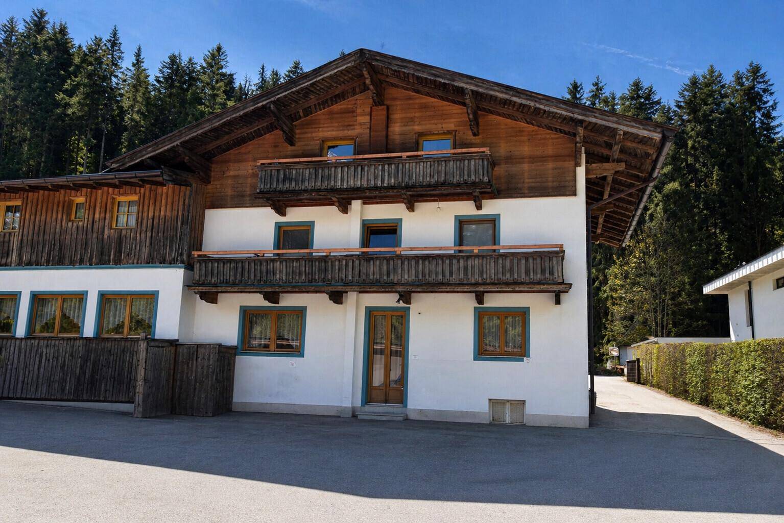 Charmantes Alpenhaus mit Holzbalkonen und Fassade, umgeben von dichtem Wald und Natur.
