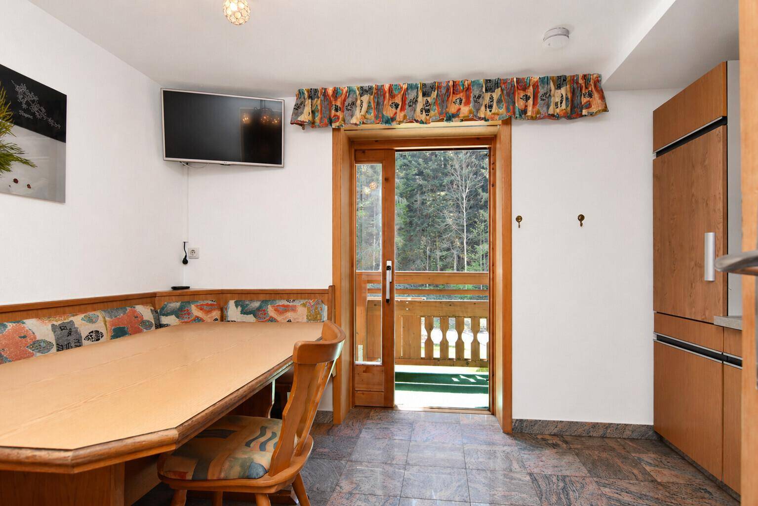 Gemütlicher Essbereich mit Eckbank, Holztisch und direktem Zugang zum Balkon mit Waldblick.