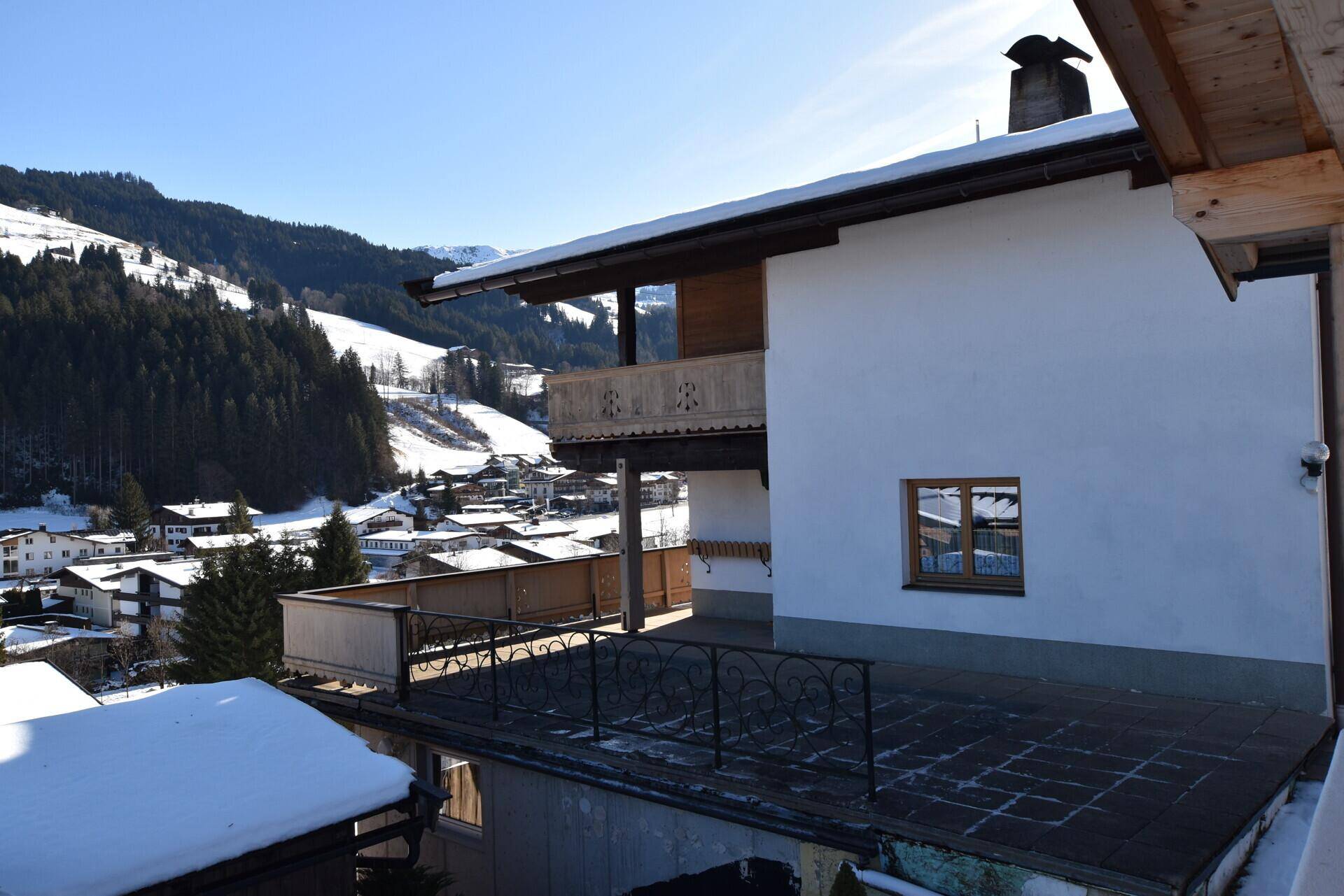 Große geflieste Terrasse mit Blick auf das verschneite Dorf und die umliegenden Berge.