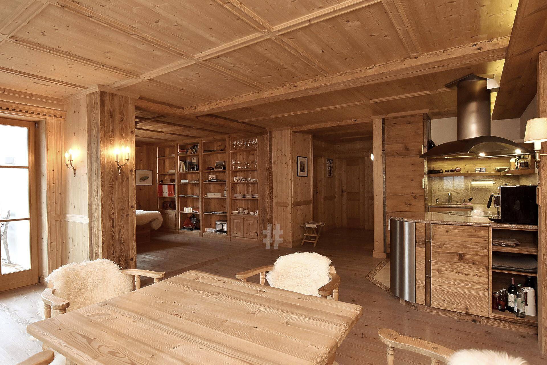 Gemütlicher offener Wohnbereich mit Holztäfelung, Essbereich und integrierter Küche im Chalet-Stil.