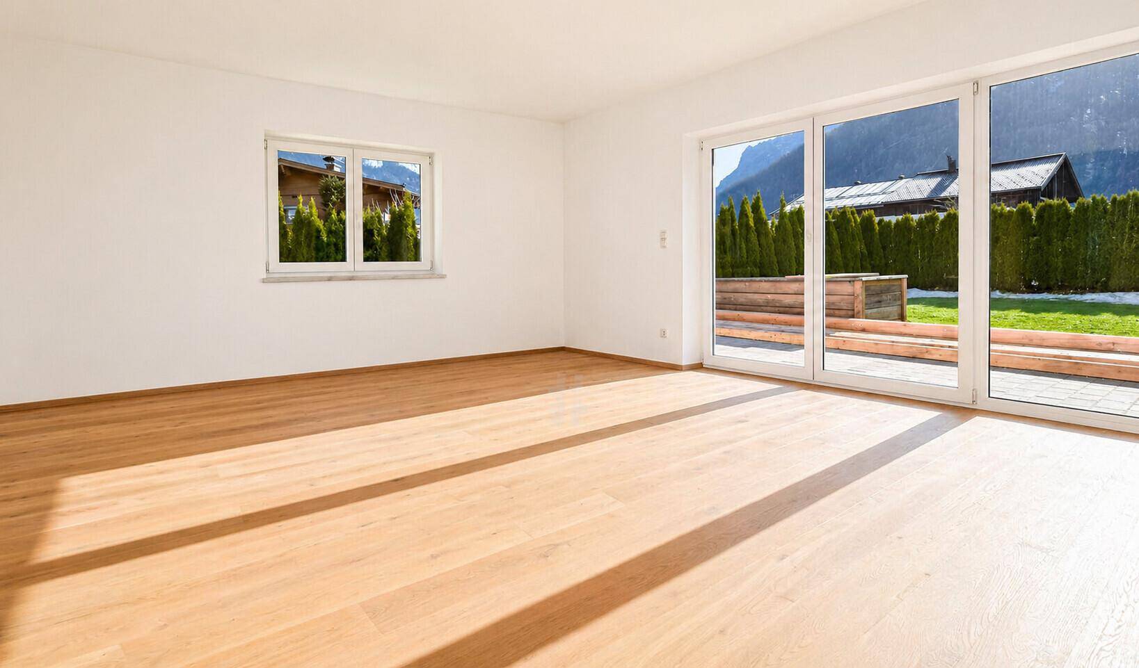 Heller Wohnraum mit Holzboden, großen Schiebetüren und Zugang zu einer Terrasse.