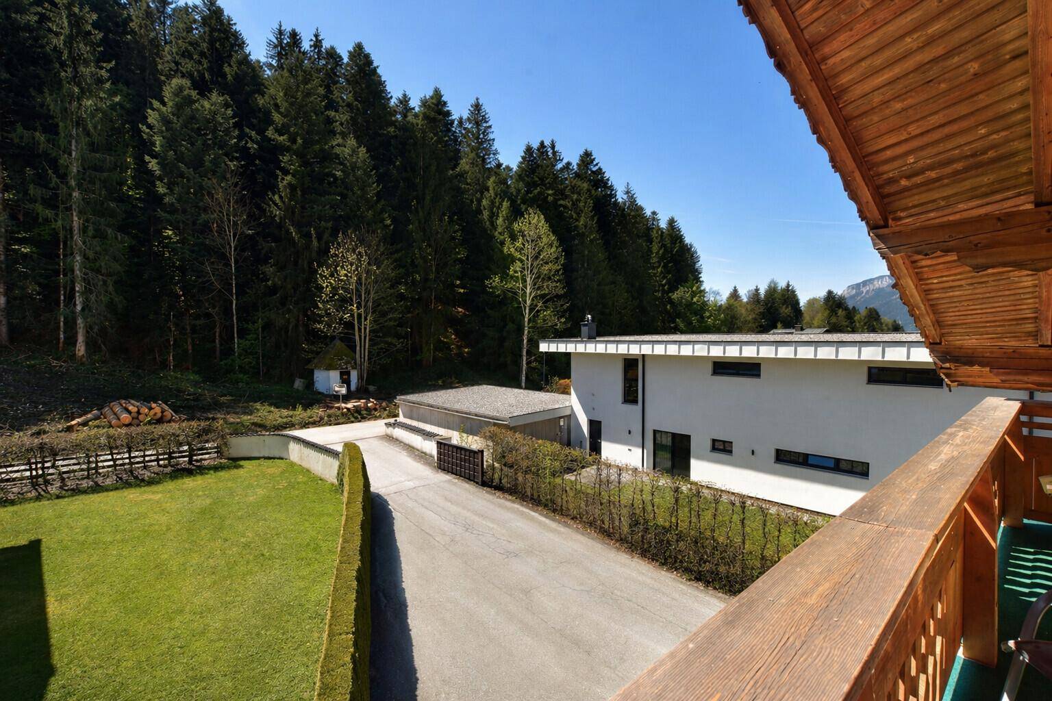 Weitläufiger Blick auf die Umgebung mit einem modernen Gebäude, Zufahrt und angrenzendem Wald.