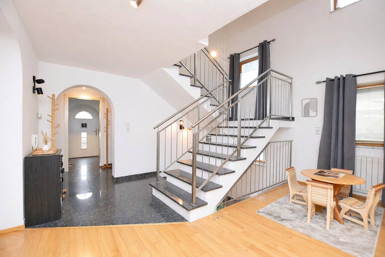 Heller Eingangsbereich mit moderner Treppe, Holzfußboden und kleinem Essbereich.