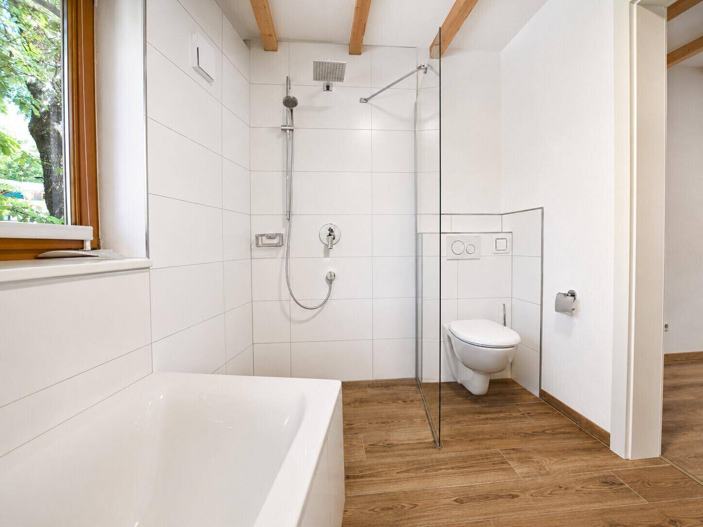 Helles Badezimmer mit Badewanne, Dusche und wandhängendem WC.