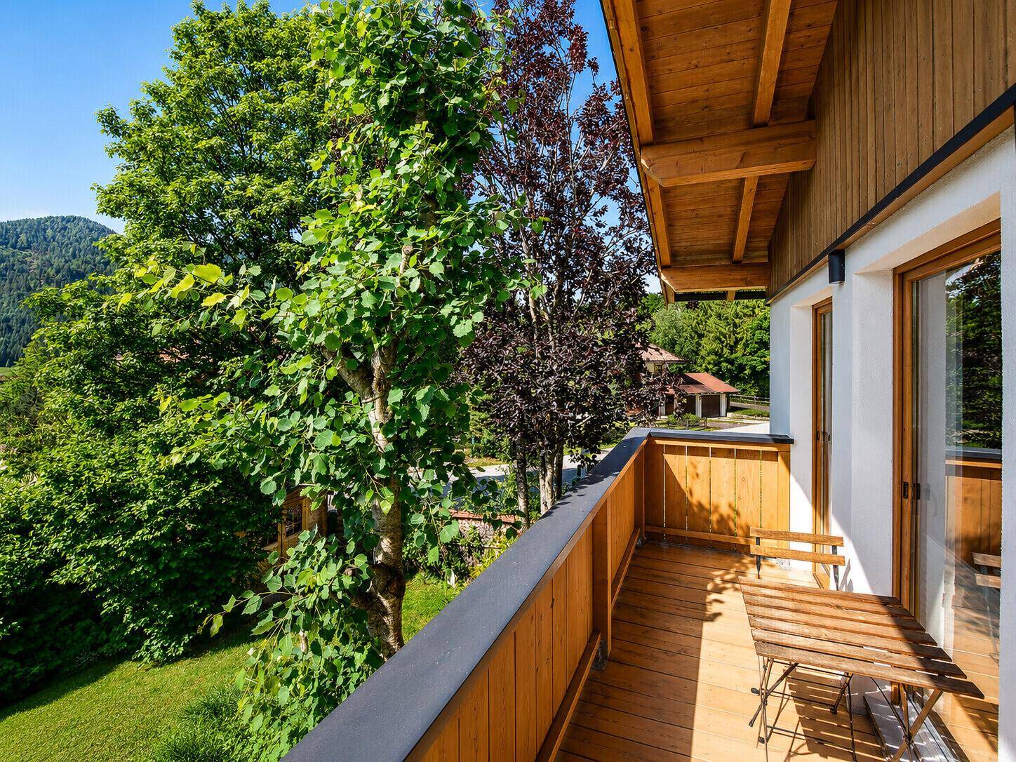 Geräumiger Holzbalkon mit Sitzgelegenheiten und weitem Blick ins Grüne.