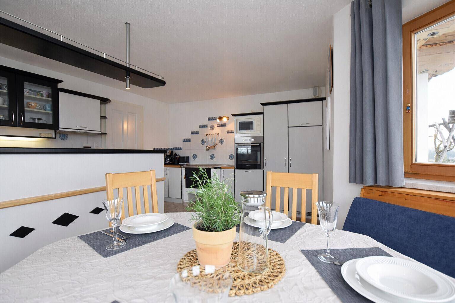Gemütlicher Essbereich mit Holztisch, Sitzbank und Blick in die angrenzende Küche.