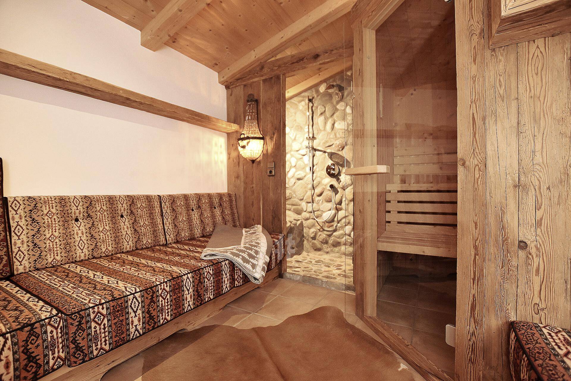 Entspannender Wellnessbereich mit Sauna, Steindusche und gemütlicher Sitzgelegenheit im Chalet.