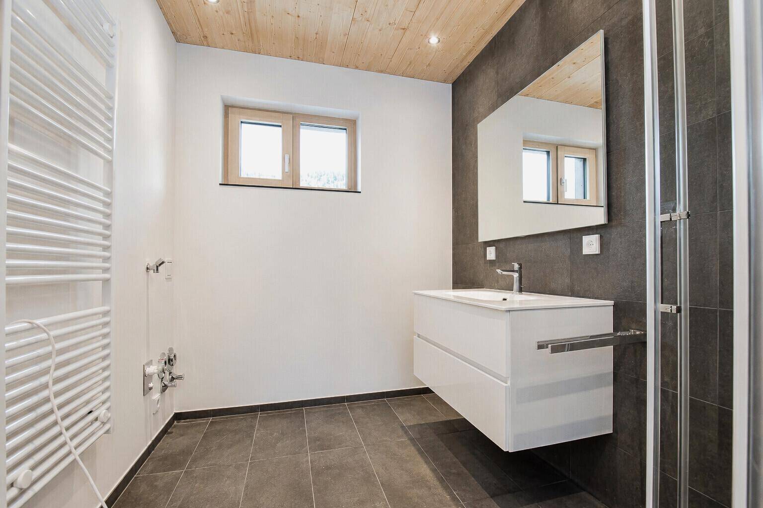 Modernes Badezimmer mit schwebendem Waschtisch, Dusche und beheiztem Handtuchhalter.
