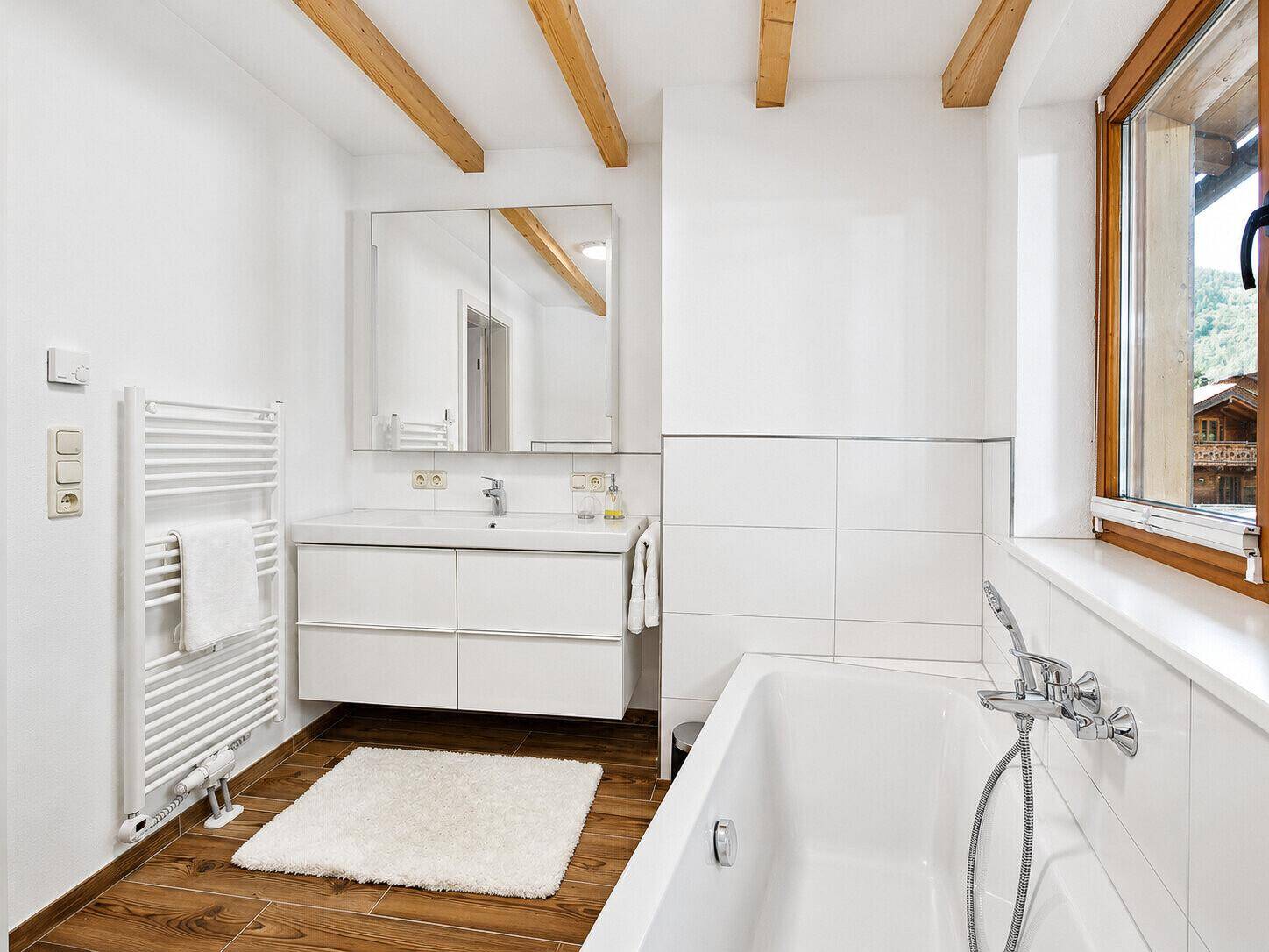 Modernes Badezimmer mit Badewanne, Waschbecken und großem Spiegel.