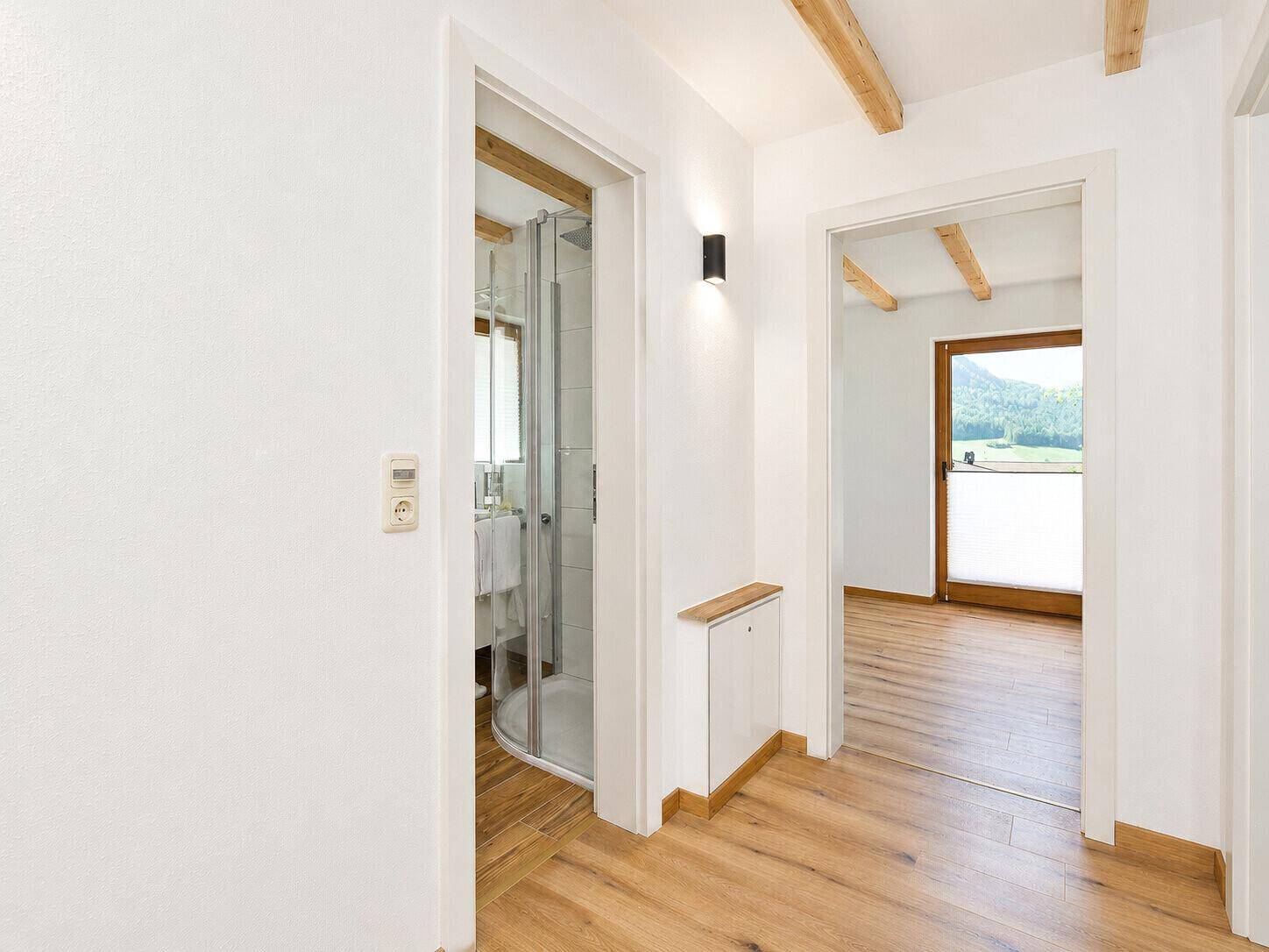 Heller Flur mit Holzboden und Zugang zu Bad und Schlafzimmer.