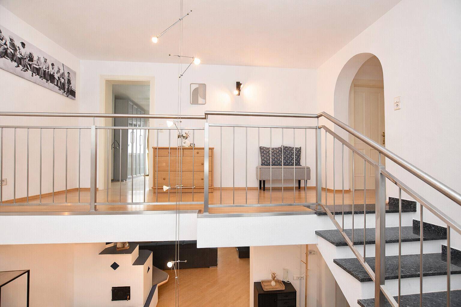 Helle Galerie im Obergeschoss mit Blick auf den Wohnbereich und moderne Treppe.