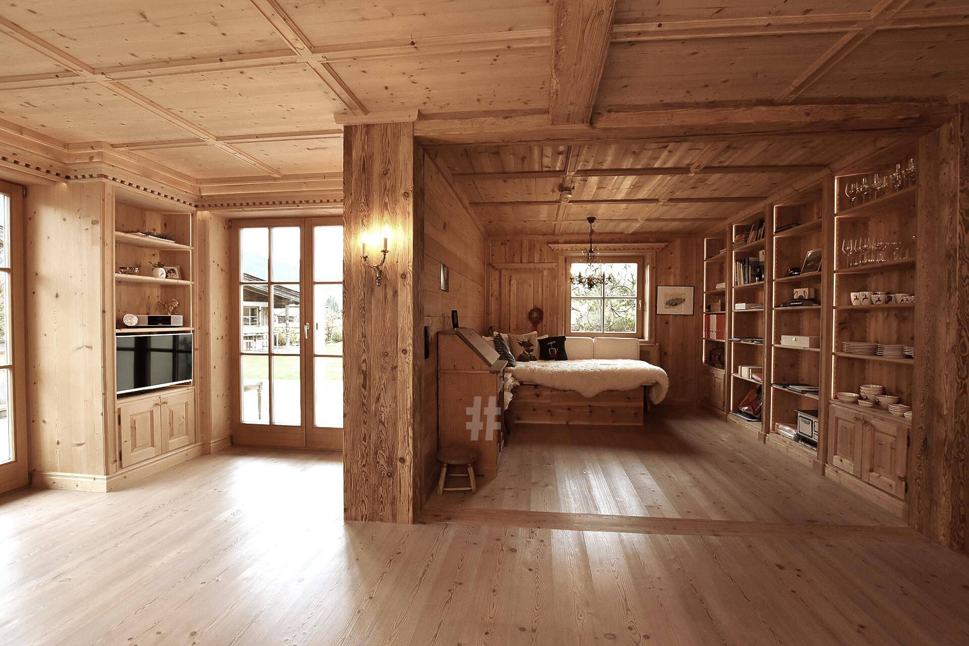 Geräumiger Wohnbereich mit Holzeinbauten, Bücherregalen und gemütlicher Sitzecke im Chalet-Stil.