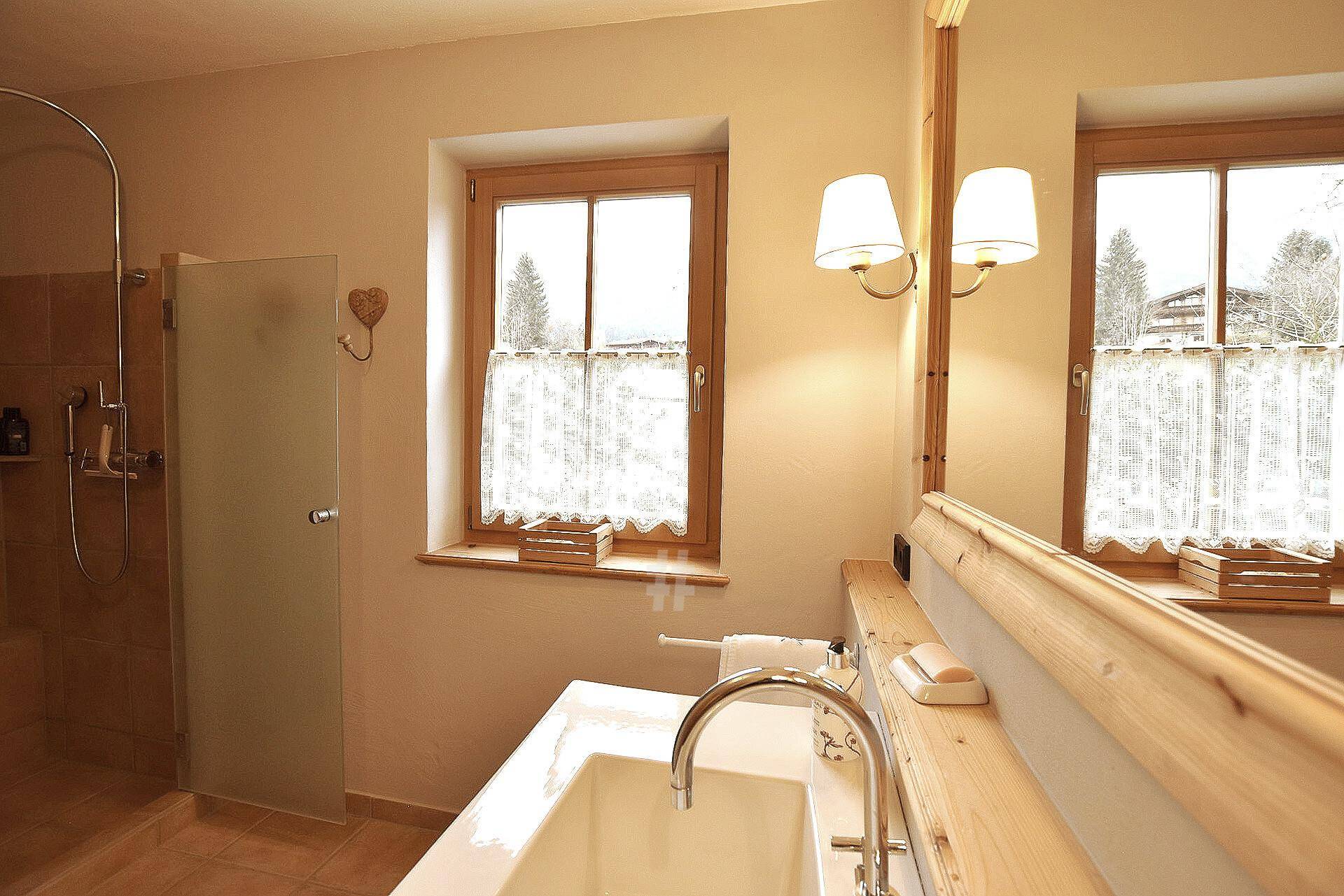 Helles Badezimmer im Landhausstil mit Fenster, Einzelwaschbecken und Duschbereich.
