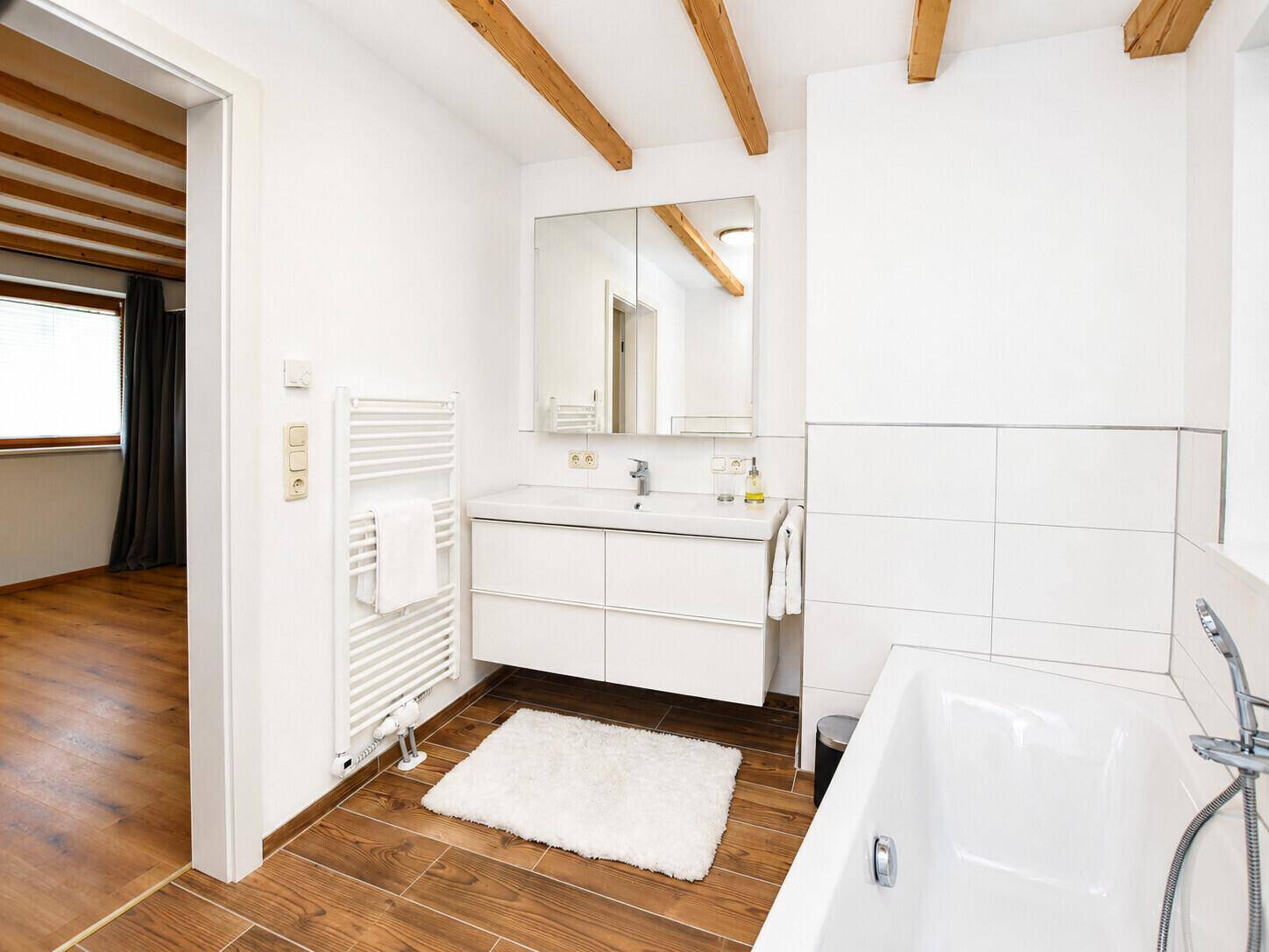 Modernes Badezimmer mit Badewanne, Waschbecken und beheiztem Handtuchhalter.