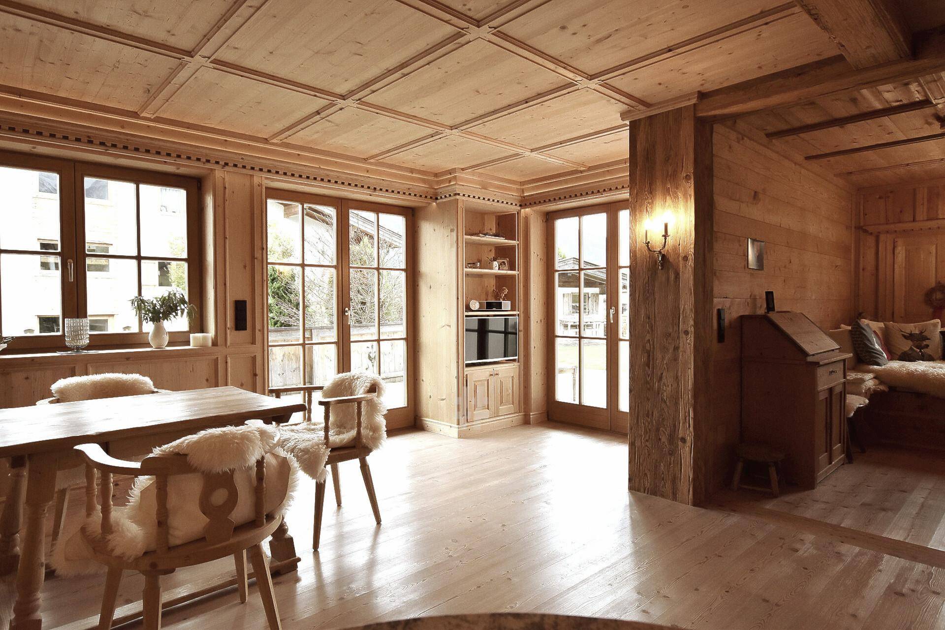 Heller Wohn- und Essbereich mit viel Holz, großen Fenstern und Zugang zum Außenbereich.