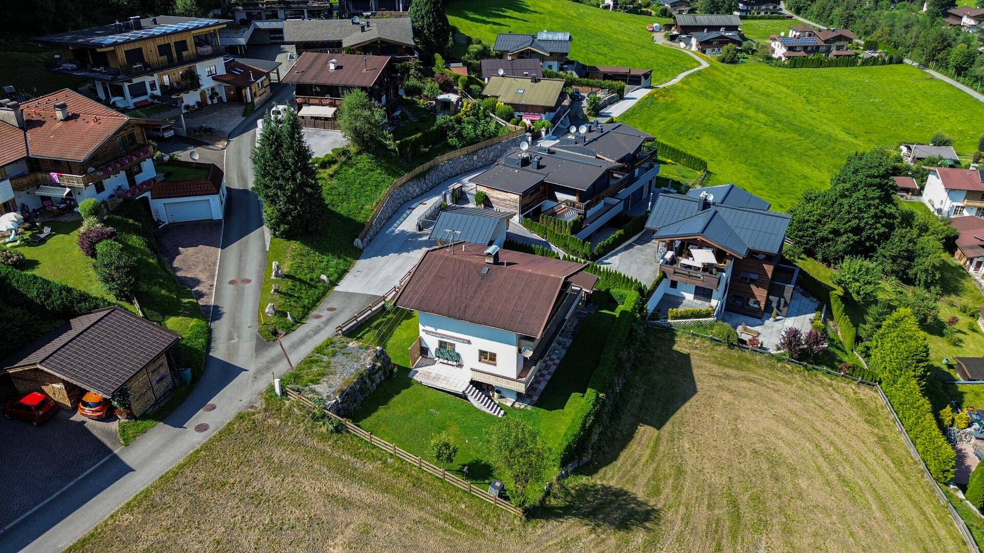 Weitläufige Luftaufnahme des Einfamilienhauses in einer ländlichen Wohnsiedlung mit viel Grün.