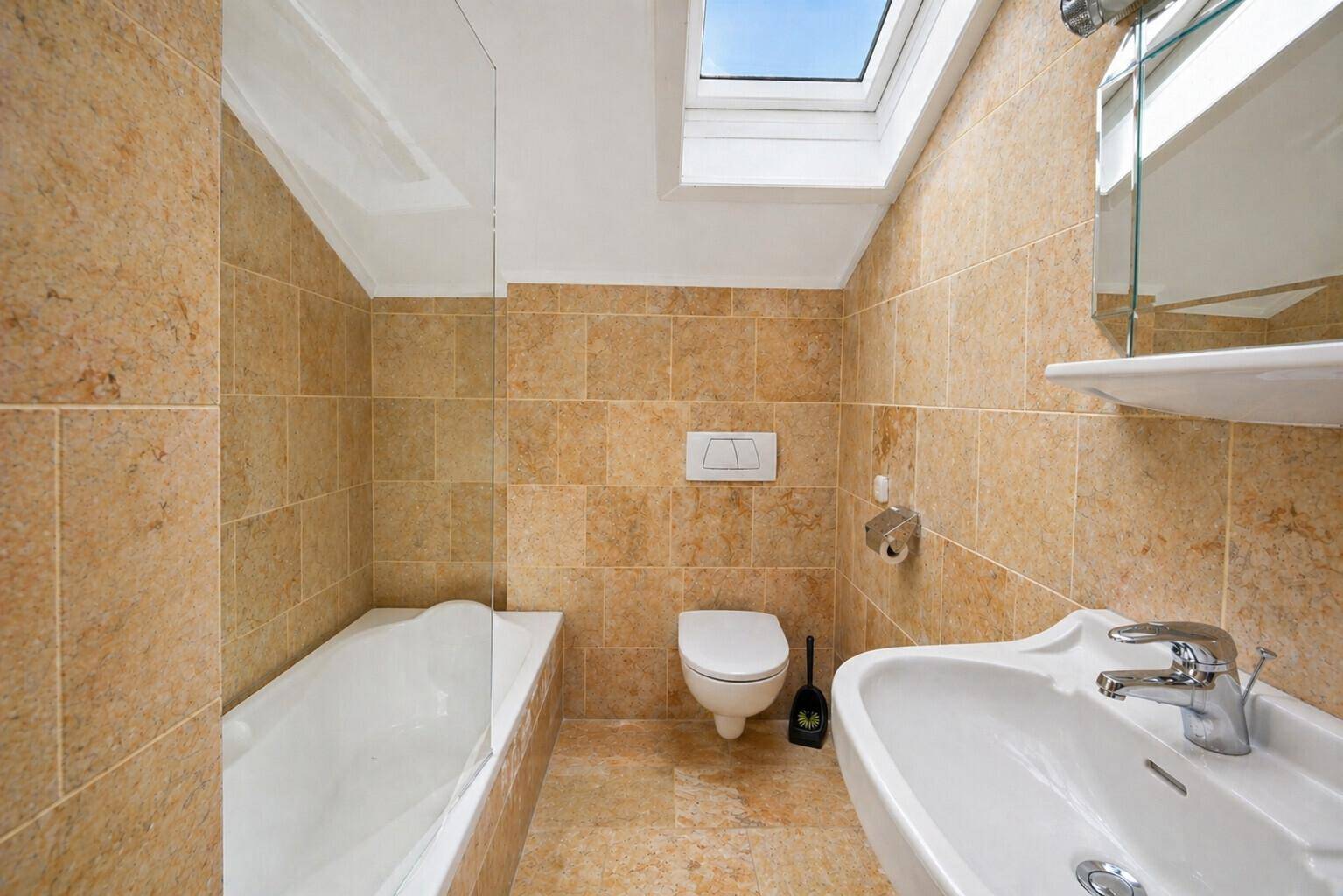 Modernes Badezimmer mit beigen Fliesen, Badewanne, wandhängendem WC und einem Dachfenster.