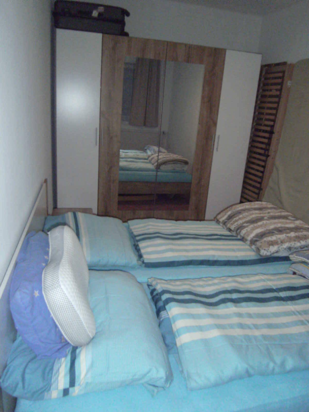 Gemütliches Schlafzimmer mit einem Bett und einem Kleiderschrank mit Spiegeltüren.