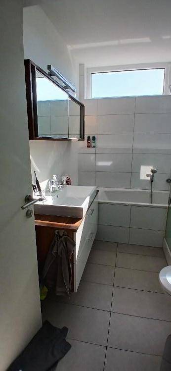 Helles Badezimmer mit Badewanne, Waschbecken und Fenster für natürliches Tageslicht.