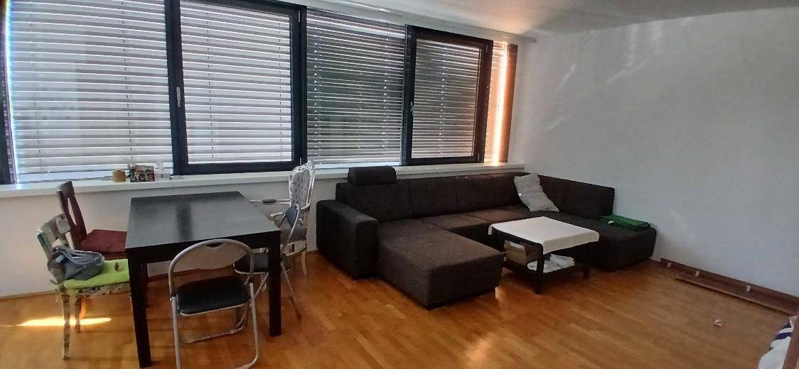Geräumiger Wohn- und Essbereich mit dunklem Sofa, Esstisch und großen Fenstern.