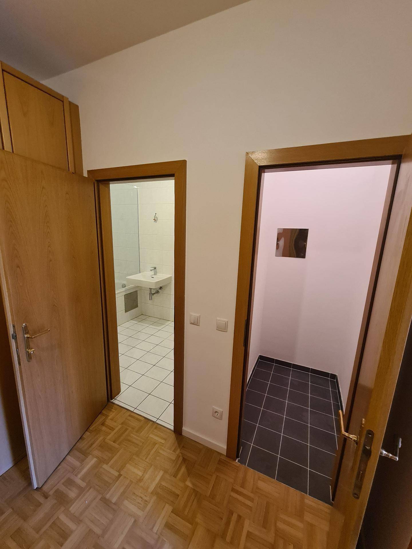 Flur mit Parkettboden und Zugang zu einem Badezimmer und einem weiteren Raum.