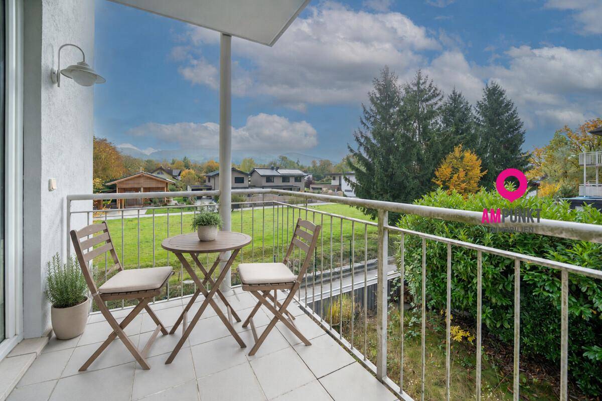 Gemütlicher Balkon mit Sitzgelegenheiten und weitem Blick ins Grüne und auf die Berge.