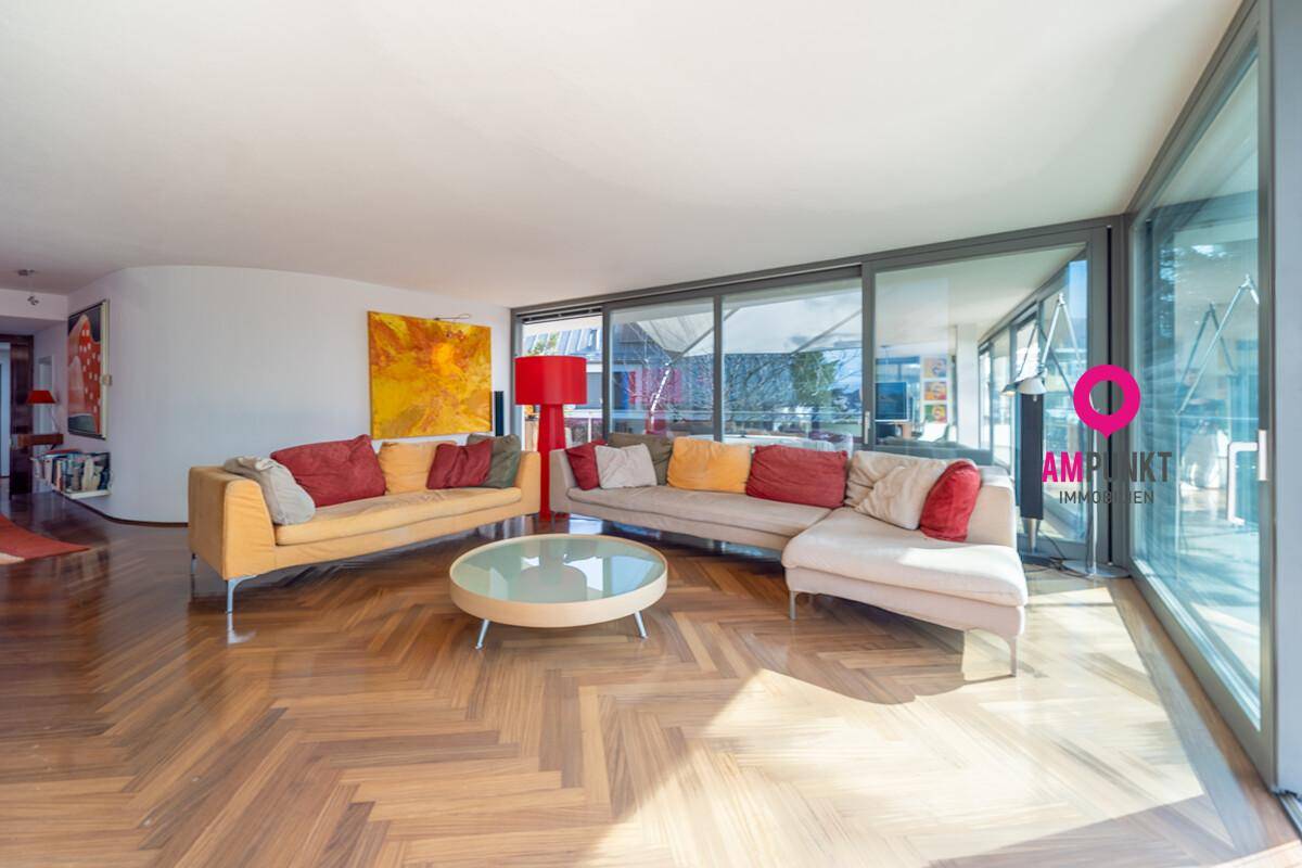Helles Wohnzimmer mit bequemen Sofas, Holzboden und großen Fensterfronten.