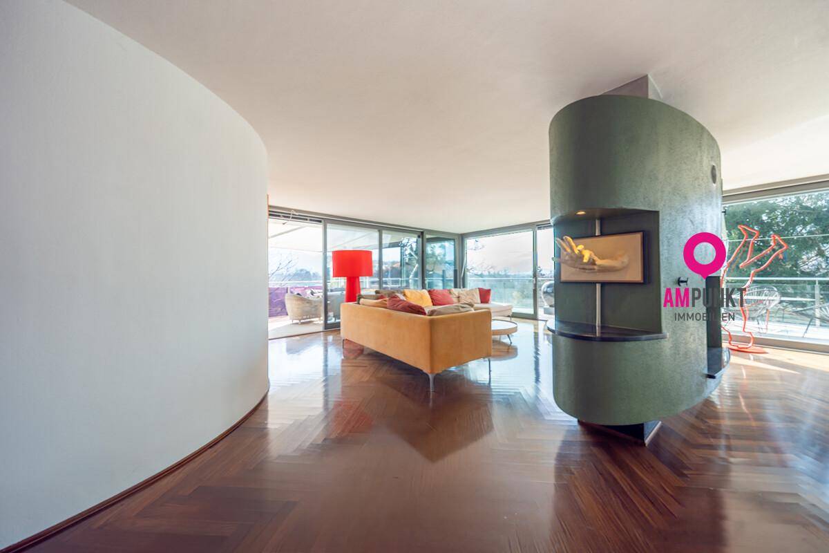 Großzügiges Wohnzimmer mit modernem Kamin, Holzboden und Zugang zur Terrasse.