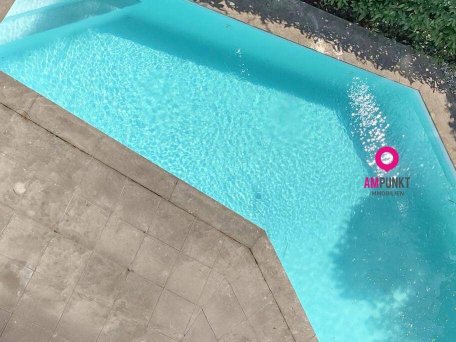Außenpool mit klarem Wasser und umliegender Steinfläche.