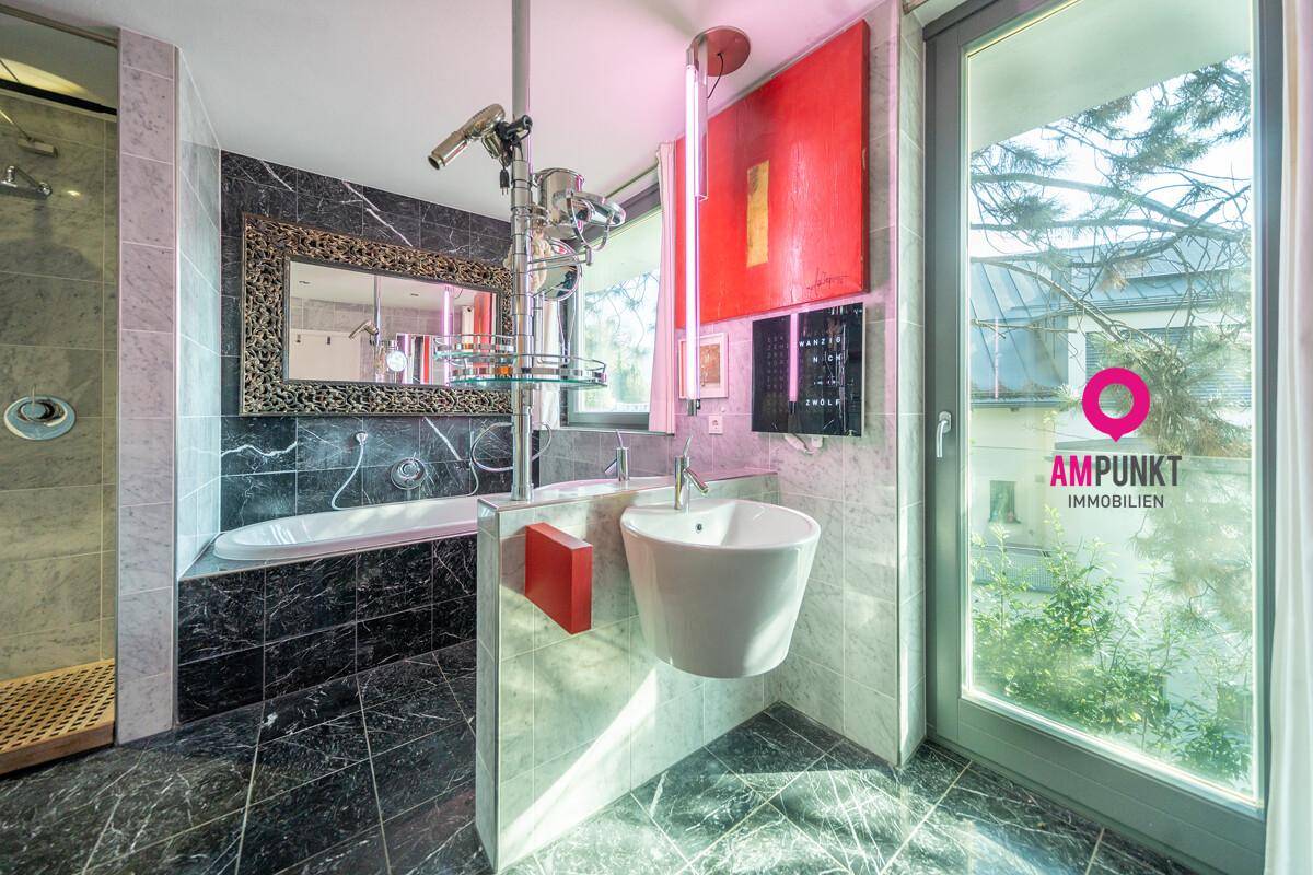 Modernes Badezimmer mit Badewanne, Waschbecken und großem Fenster für Tageslicht.