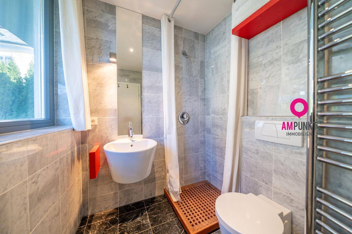 Funktionales Badezimmer mit Dusche, WC, Waschbecken und beheiztem Handtuchhalter.