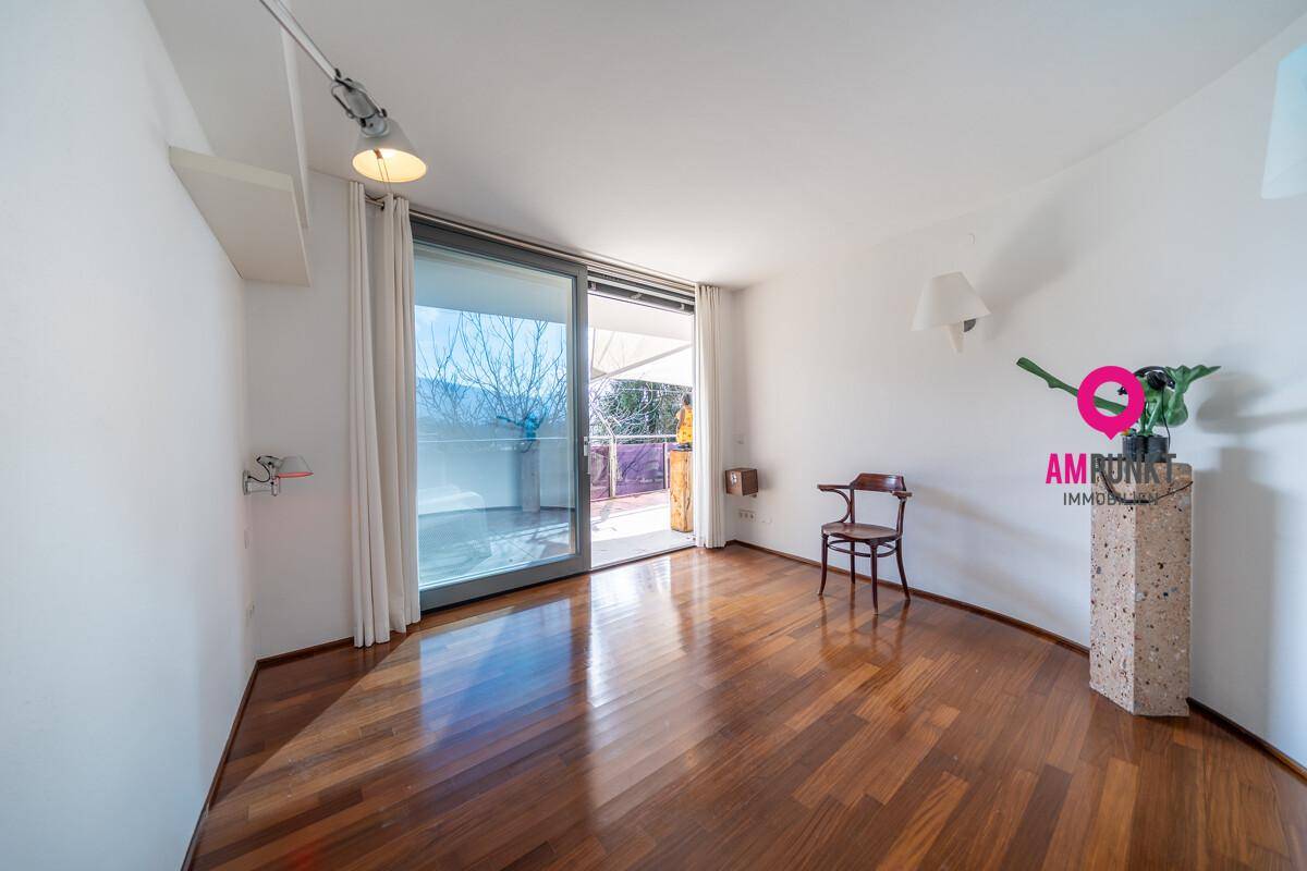 Heller Raum mit Holzboden und großem Schiebefenster zum Außenbereich.