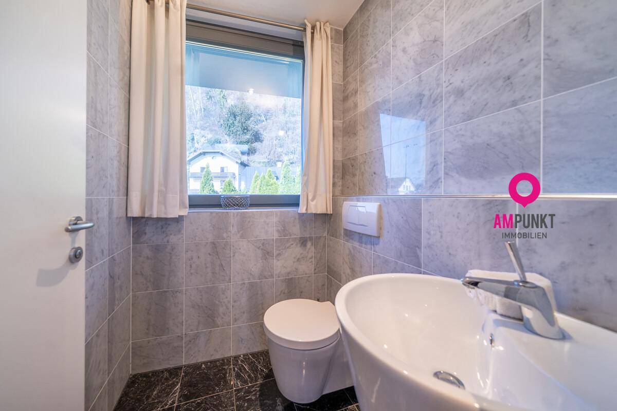 Helles Gäste-WC mit Fenster, wandhängender Toilette und modernem Waschbecken.